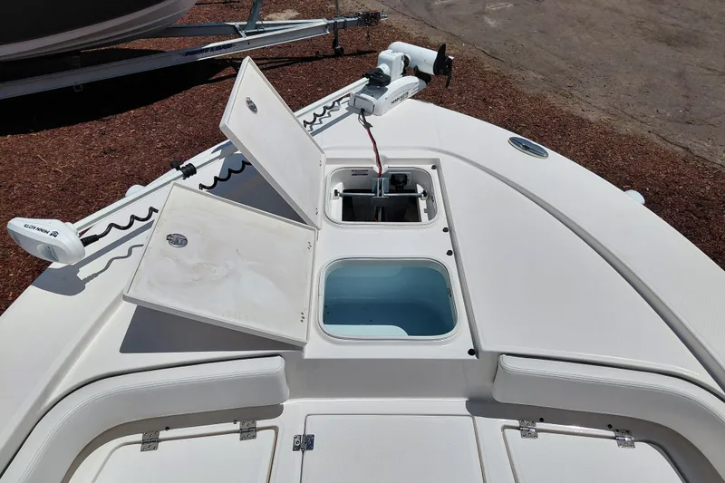 Slide: The Image of 2023 Robalo 246 Cayman boat deck with open storage compartments and trolling motor. - 16