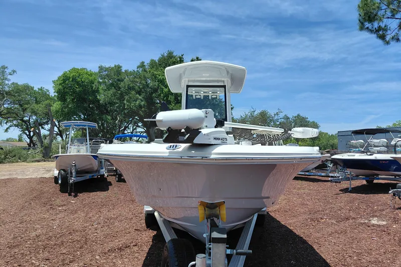 Slide: The Image of 2023 Robalo 246 Cayman boat on trailer, surrounded by trees and clear blue sky. - 2