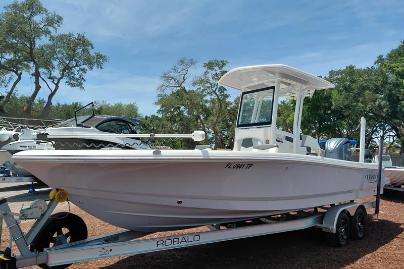 Slide: The Image of 2023 Robalo 246 Cayman boat on trailer, parked outdoors under clear sky. - 3