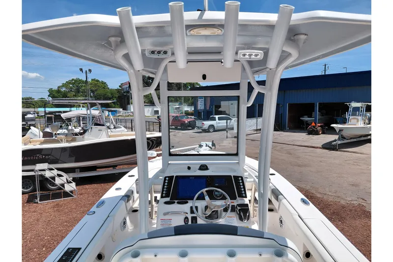 Slide: The Image of 2023 Robalo 246 Cayman boat cockpit with advanced navigation system and T-top in a marina setting. - 34