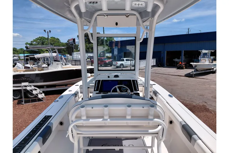 Slide: The Image of 2023 Robalo 246 Cayman boat interior with helm, parked at a marina under clear skies. - 36