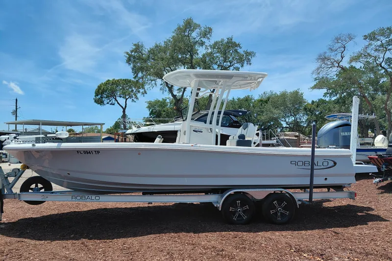 Slide: The Image of 2023 Robalo 246 Cayman boat on trailer, parked outdoors under clear blue sky. - 4