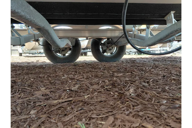 Slide: The Image of Underneath view of a 2023 Robalo 246 Cayman boat trailer on mulch ground. - 58