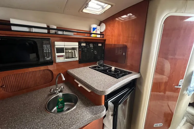 Slide: The Image of 2005 Rinker Fiesta Vee 320 boat kitchen with microwave, stove, and sink. - 2