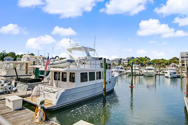 Slide: The Image of 2022 North Pacific 45 Pilothouse yacht docked in a marina under a clear blue sky. - 4