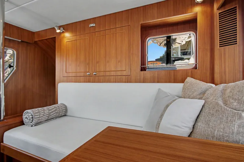 Slide: The Image of Interior of 2022 North Pacific 45 Pilothouse with wooden paneling and cozy seating area. - 20