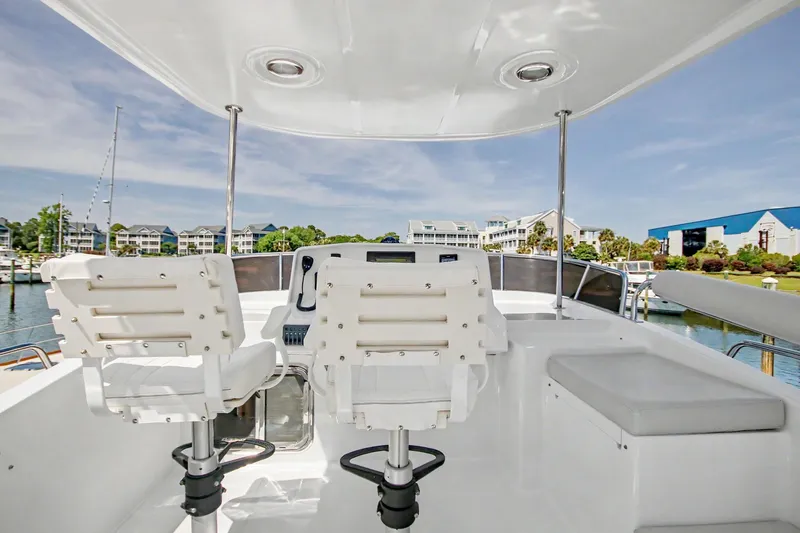 Slide: The Image of Pilothouse of 2022 North Pacific 45 yacht with dual white captain chairs, marina view. - 37