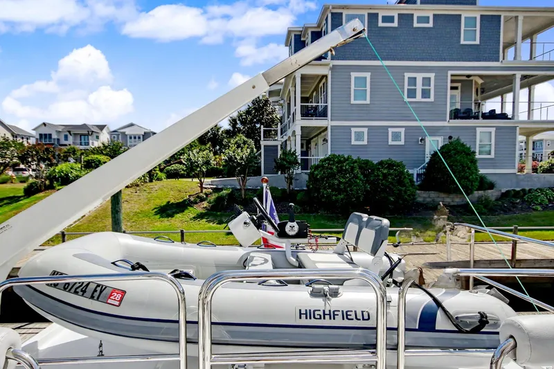 Slide: The Image of Inflatable boat on North Pacific 45 Pilothouse, 2022, docked near modern waterfront homes. - 40