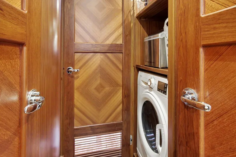 Slide: The Image of Laundry area with washer in 2022 North Pacific 45 Pilothouse, featuring elegant wood cabinetry. - 26