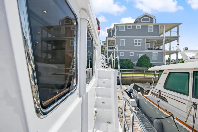 Slide: The Image of 2022 North Pacific 45 Pilothouse yacht docked beside a modern waterfront home. - 44