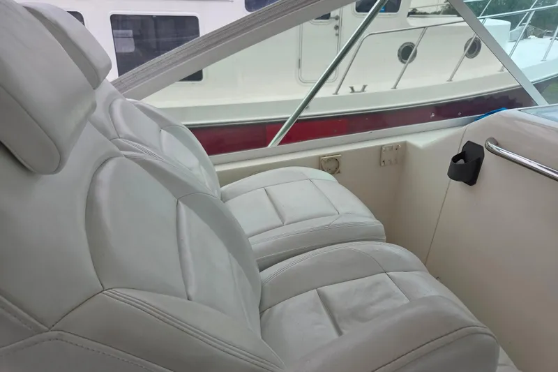 Slide: The Image of Interior seating of a 1999 Cabo 35 Express boat, featuring white leather upholstery. - 14