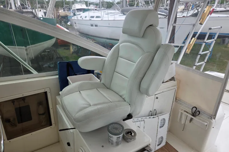 Slide: The Image of Captain's chair on a 1999 Cabo 35 Express boat, surrounded by docked vessels. - 18