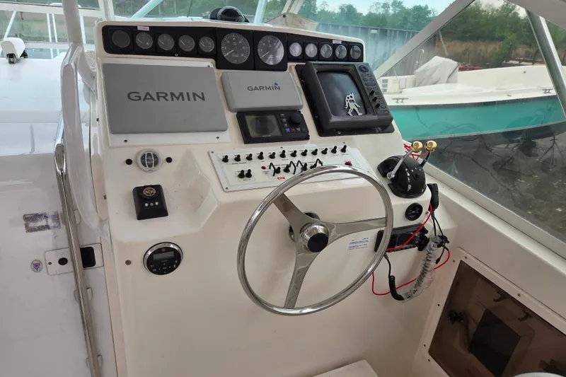 Slide: The Image of 1999 Cabo 35 Express boat helm with Garmin navigation system and steering wheel. - 22