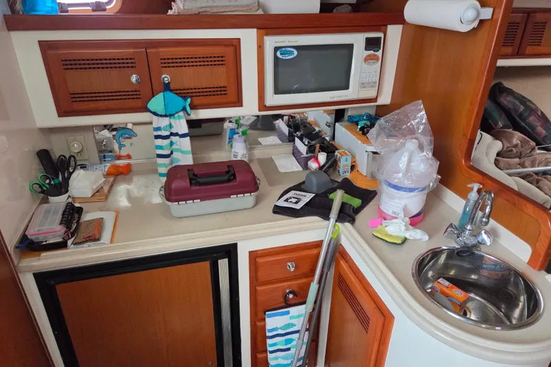 Slide: The Image of Compact kitchen area in a 1999 Cabo 35 Express boat, featuring a microwave and sink. - 23
