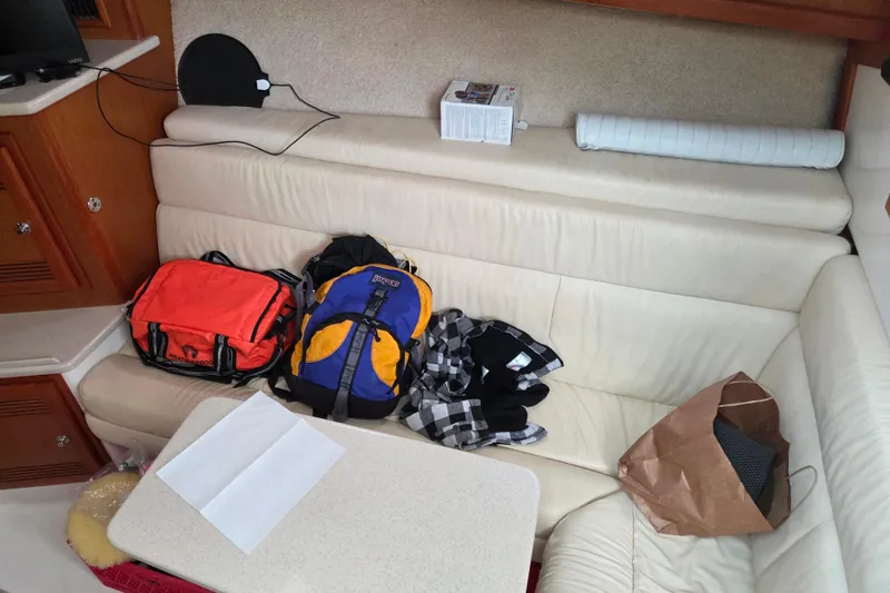 Slide: The Image of Interior of a 1999 Cabo 35 Express with bags and items on a cream sofa. - 24