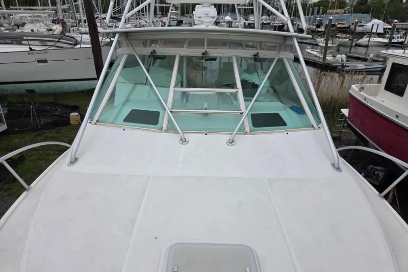Slide: The Image of 1999 Cabo 35 Express boat docked at a marina, showcasing its front deck and windshield. - 32