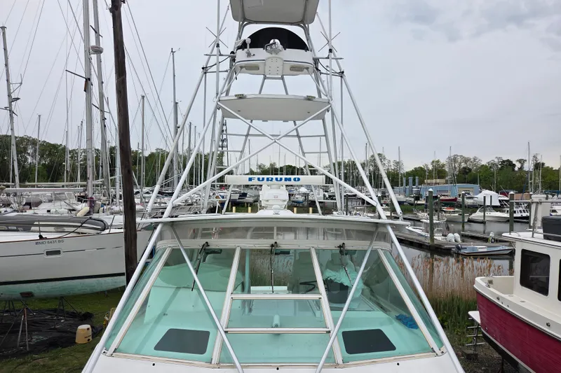 Slide: The Image of 1999 Cabo 35 Express boat with tower, docked in a marina with sailboats. - 33