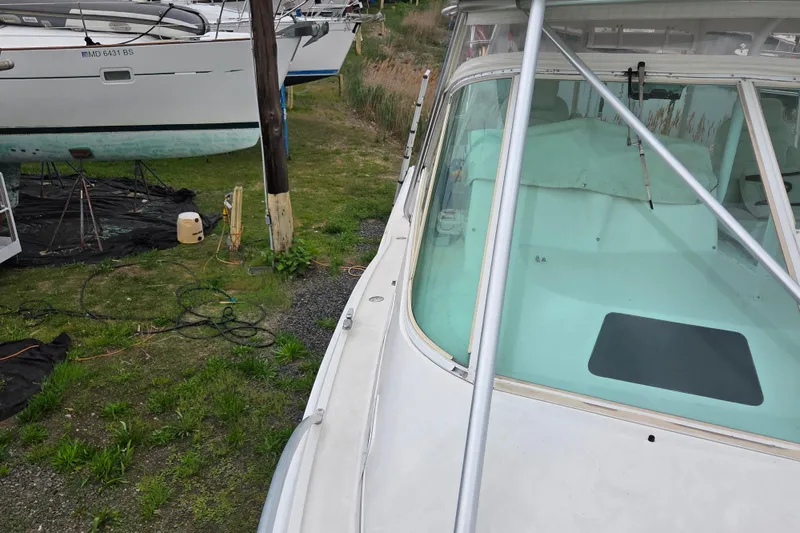 Slide: The Image of 1999 Cabo 35 Express boat on land, near other vessels, with visible windshield and deck. - 35
