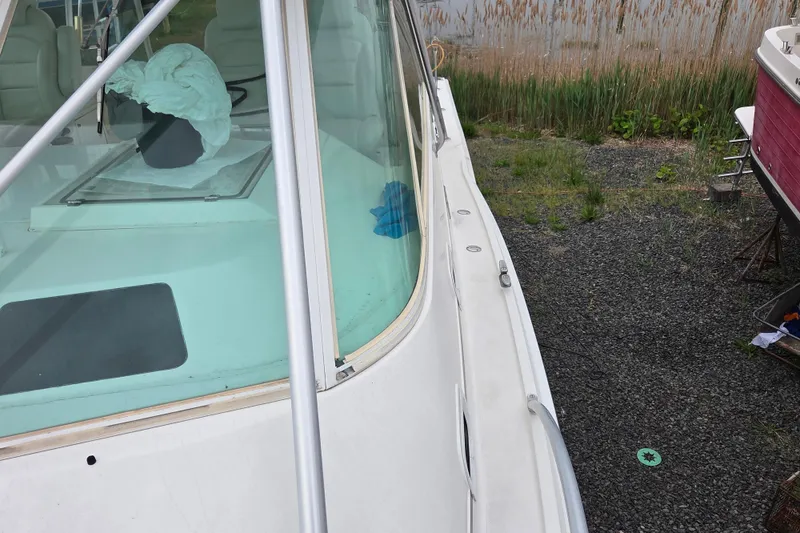 Slide: The Image of 1999 Cabo 35 Express boat on gravel, showcasing deck and windshield details. - 37