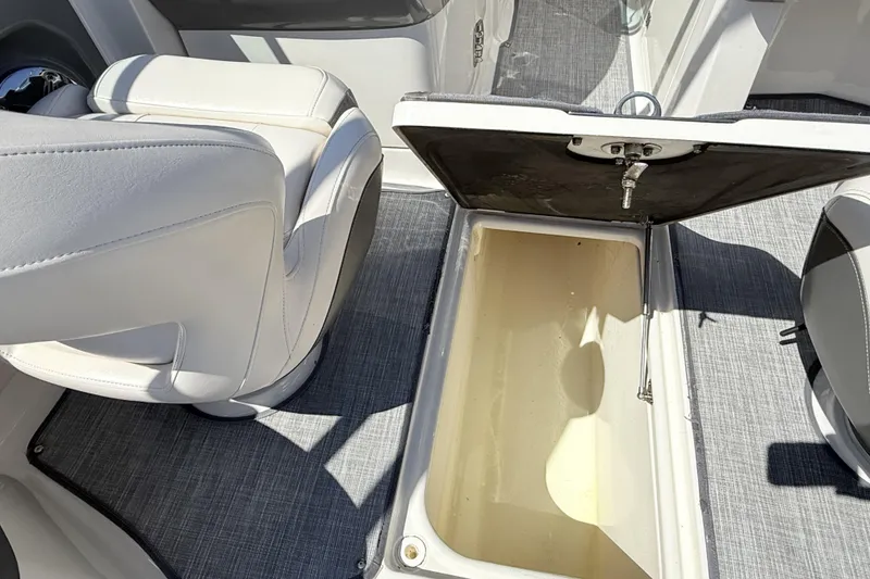 Slide: The Image of 2016 Chaparral 246 SSi boat interior with open storage compartment and white seating. - 16