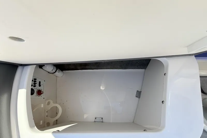 Slide: The Image of Storage compartment in a 2016 Chaparral 246 SSi boat, featuring control panel and fire extinguisher. - 24