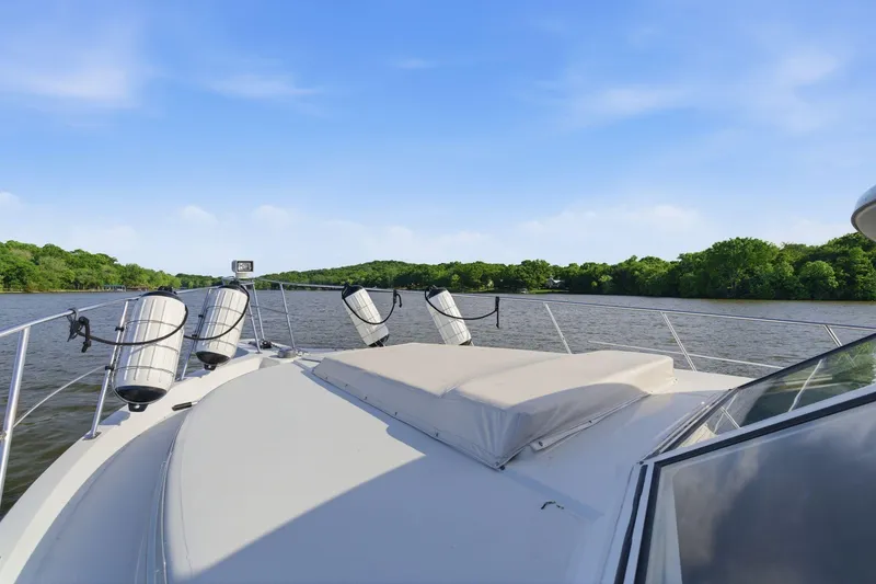 Slide: The Image of 1998 Carver 445 Aft Cabin Motor Yacht cruising on a serene river under a clear blue sky. - 18