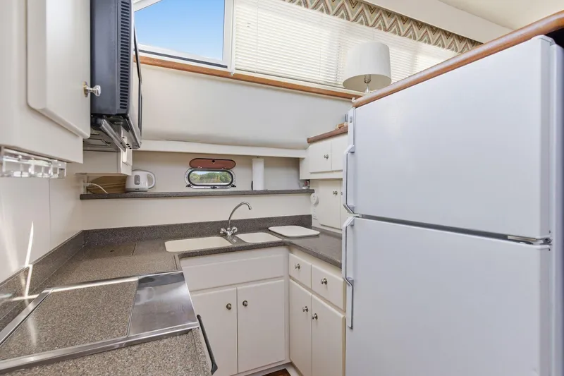 Slide: The Image of Compact kitchen in 1998 Carver 445 Aft Cabin Motor Yacht with white cabinetry and appliances. - 24