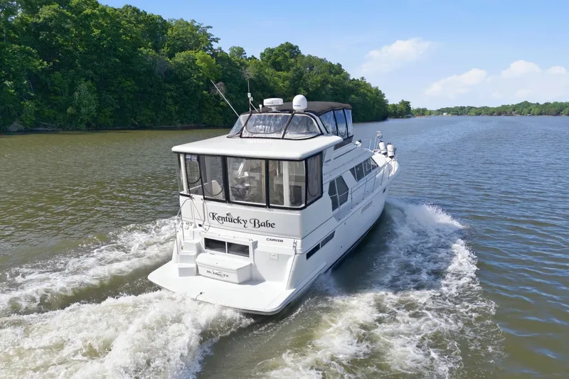 Slide: The Image of 1998 Carver 445 Aft Cabin Motor Yacht cruising on a scenic river. - 4