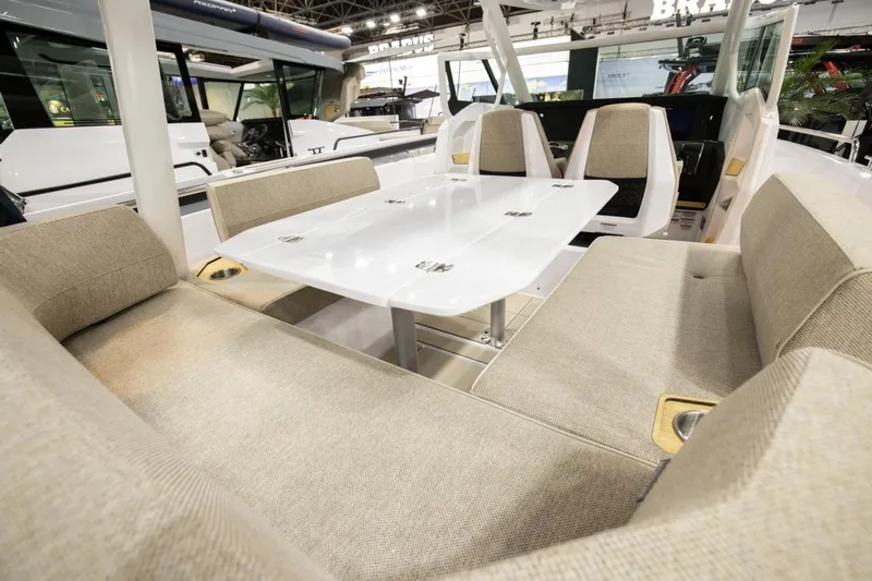 Slide: The Image of 2026 Axopar 29 Sun-Top boat interior with beige seating and white table. - 7