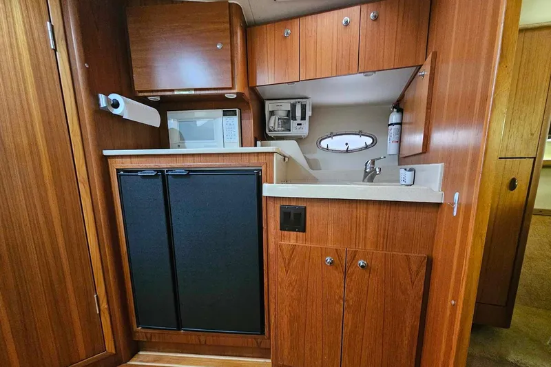 Slide: The Image of 1998 Tiara Yachts 3500 Open galley with wood cabinetry, sink, microwave, and compact refrigerator. - 22
