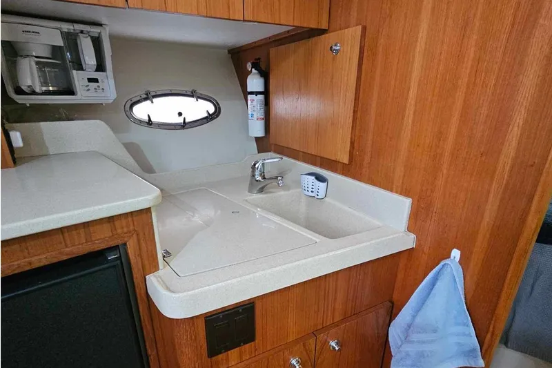 Slide: The Image of 1998 Tiara Yachts 3500 Open galley with sink, microwave, and wooden cabinetry. - 23