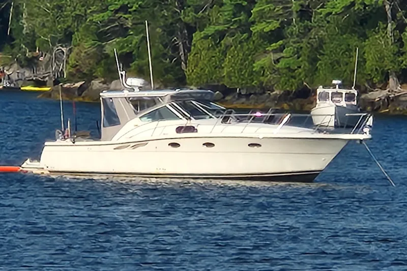 Slide: The Image of 1998 Tiara Yachts 3500 Open anchored on a serene lake with lush green shoreline. - 4