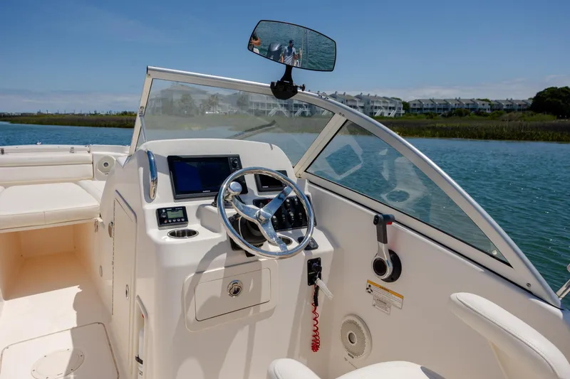 Slide: The Image of 2019 Grady-White Freedom 215 boat interior with steering wheel and dashboard on a sunny day. - 17