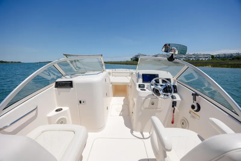Slide: The Image of 2019 Grady-White Freedom 215 boat interior with steering wheel, dashboard, and seating on water. - 21