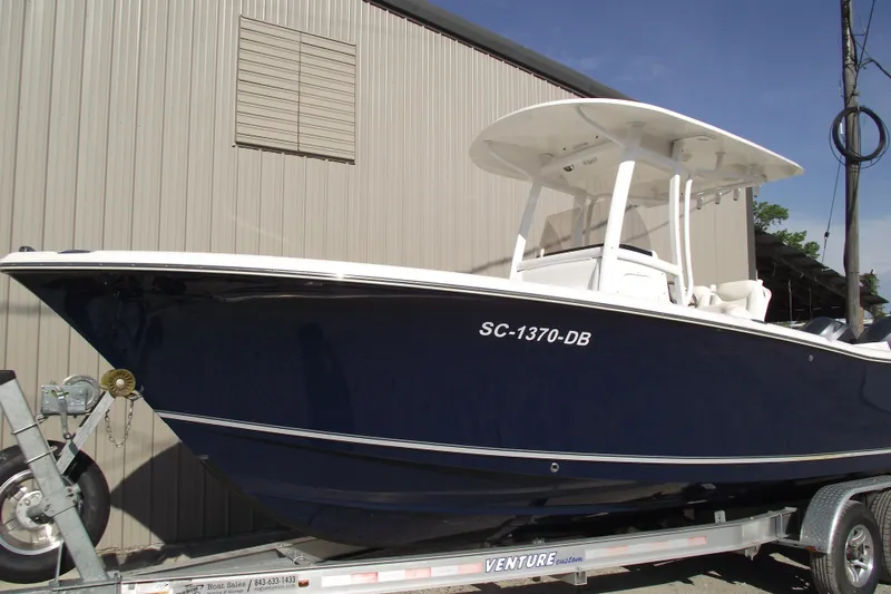 The Image of 2014 Sea Hunt Gamefish 25 boat on trailer, parked beside a building. - 1