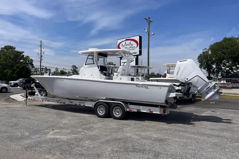Slide: The Image of 2026 Tidewater 3100 Carolina Bay boat on trailer at dealership under clear sky. - 3