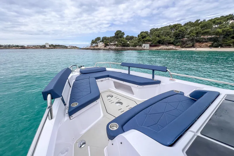 Slide: The Image of 2026 Axopar 29 XC Cross Cabin boat with blue seating, anchored in clear turquoise waters. - 11
