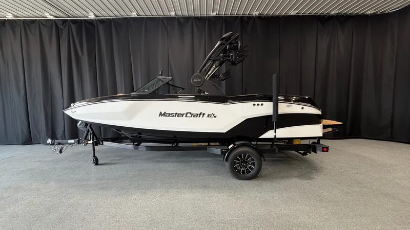 Slide: The Image of A 2027 MasterCraft NXT20 boat on a trailer in a showroom. - 0