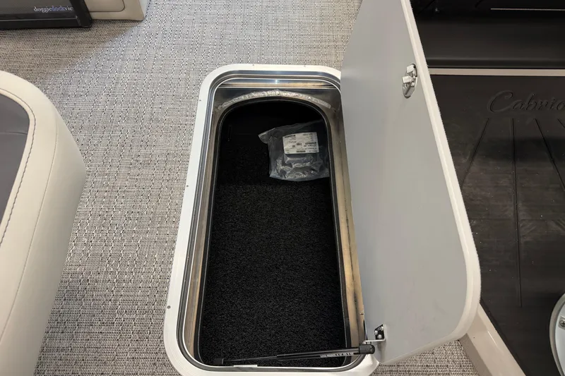 Slide: The Image of Open storage compartment in 2025 Barletta Cabrio 22UC boat, featuring carpeted interior. - 12