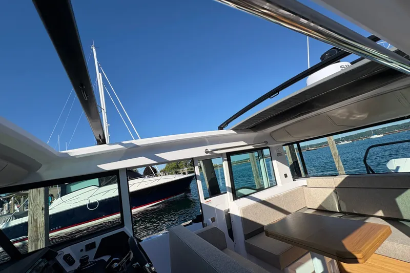 Slide: The Image of Interior view of 2026 Axopar 37 XC Cross Cabin, showcasing seating and table with ocean backdrop. - 56