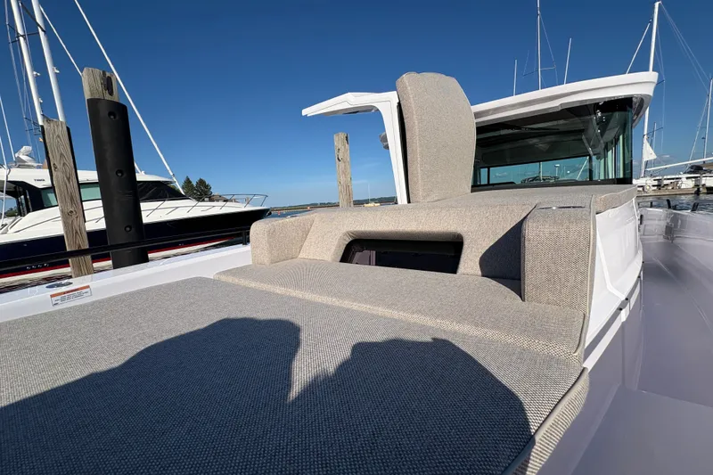 Slide: The Image of 2026 Axopar 37 XC Cross Cabin boat with cushioned seating, docked under clear blue sky. - 33