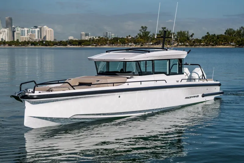 Slide: The Image of 2026 Axopar 37 XC Cross Cabin boat cruising on calm waters near a city skyline. - 2