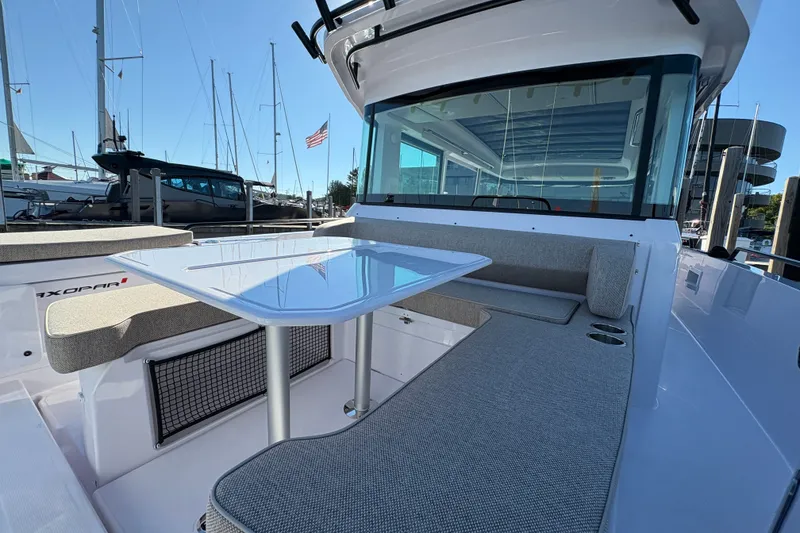 Slide: The Image of 2026 Axopar 37 XC Cross Cabin boat with sleek seating and table, docked at marina. - 17