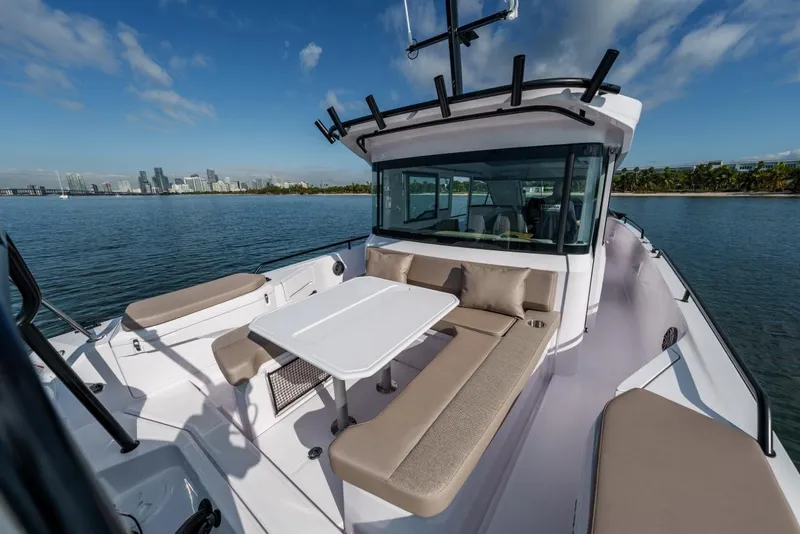 Slide: The Image of 2026 Axopar 37 XC Cross Cabin boat with spacious seating and table on calm water. - 4
