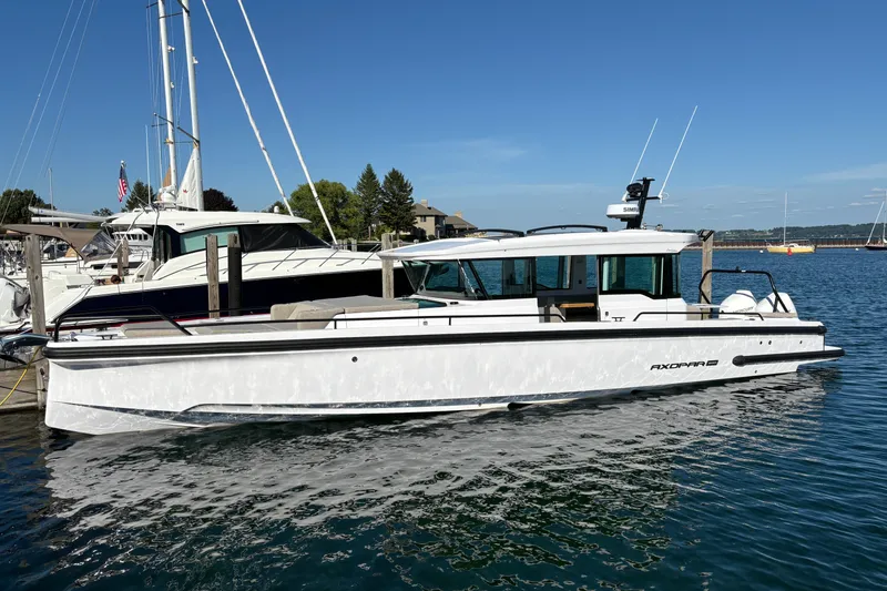 Slide: The Image of 2026 Axopar 37 XC Cross Cabin boat docked in a marina under clear blue skies. - 3