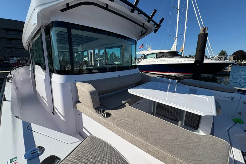 Slide: The Image of 2026 Axopar 37 XC Cross Cabin boat with seating and table, docked at marina. - 22