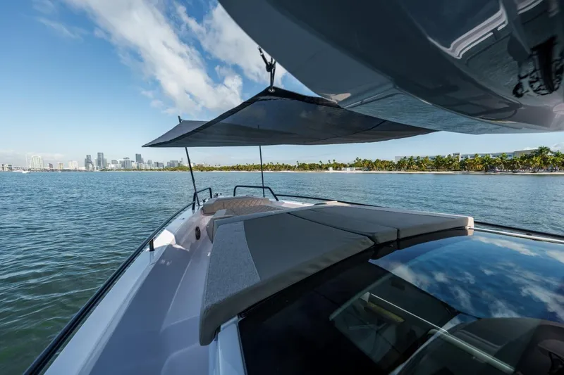 Slide: The Image of 2026 Axopar 37 XC Cross Cabin cruising near a city skyline and palm-lined shore. - 7
