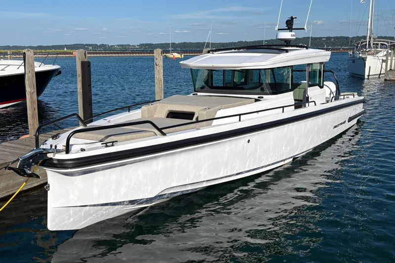 Slide: The Image of 2026 Axopar 37 XC Cross Cabin boat docked in a marina, under clear blue skies. - 4