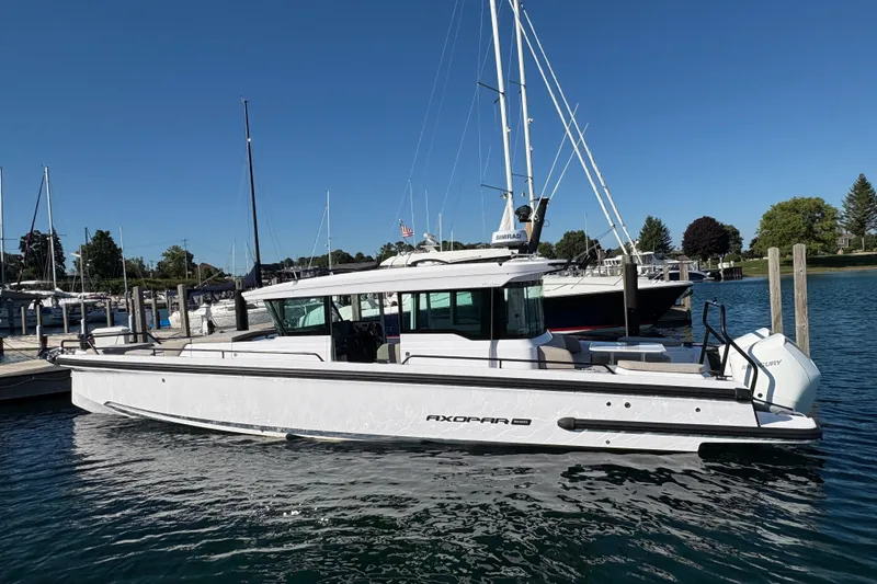 Slide: The Image of 2026 Axopar 37 XC Cross Cabin boat docked in a marina under clear blue skies. - 1