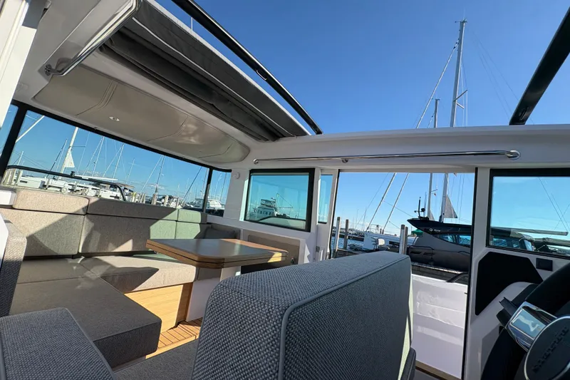 Slide: The Image of Interior of 2026 Axopar 37 XC Cross Cabin with seating and table, docked at marina. - 58